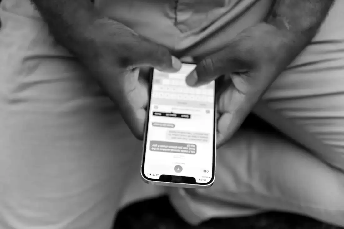 Des mains tiennent un téléphone affichant une conversation de messagerie