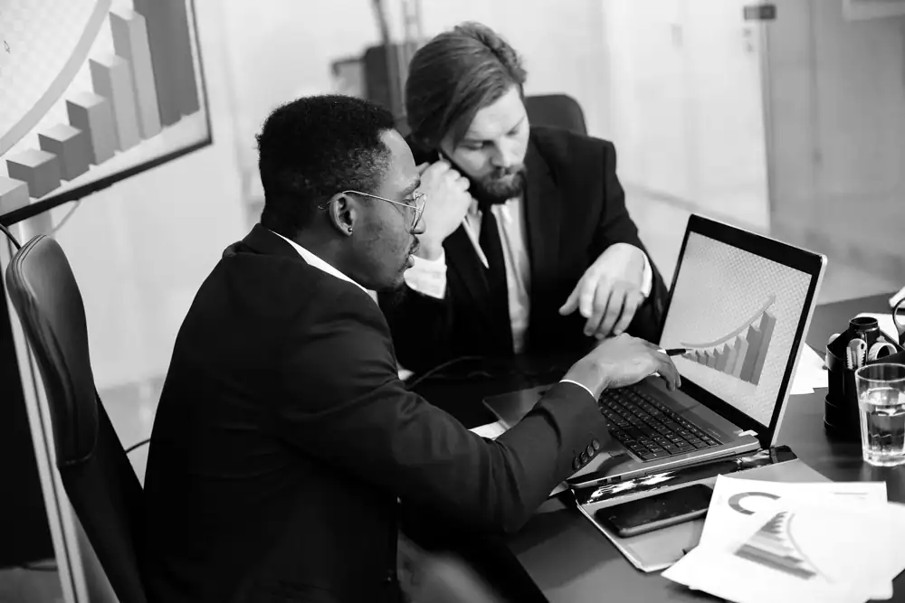 Two managers look at a chart on a computer
