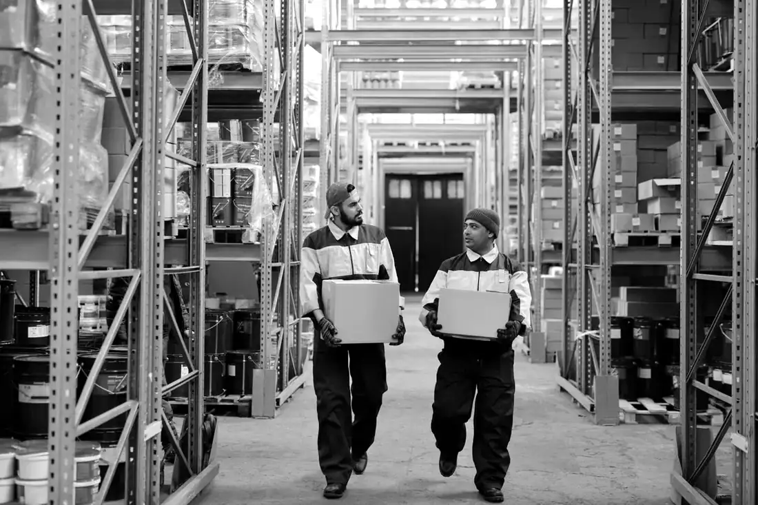 Deux préparateurs transportent des cartons dans un entrepôt