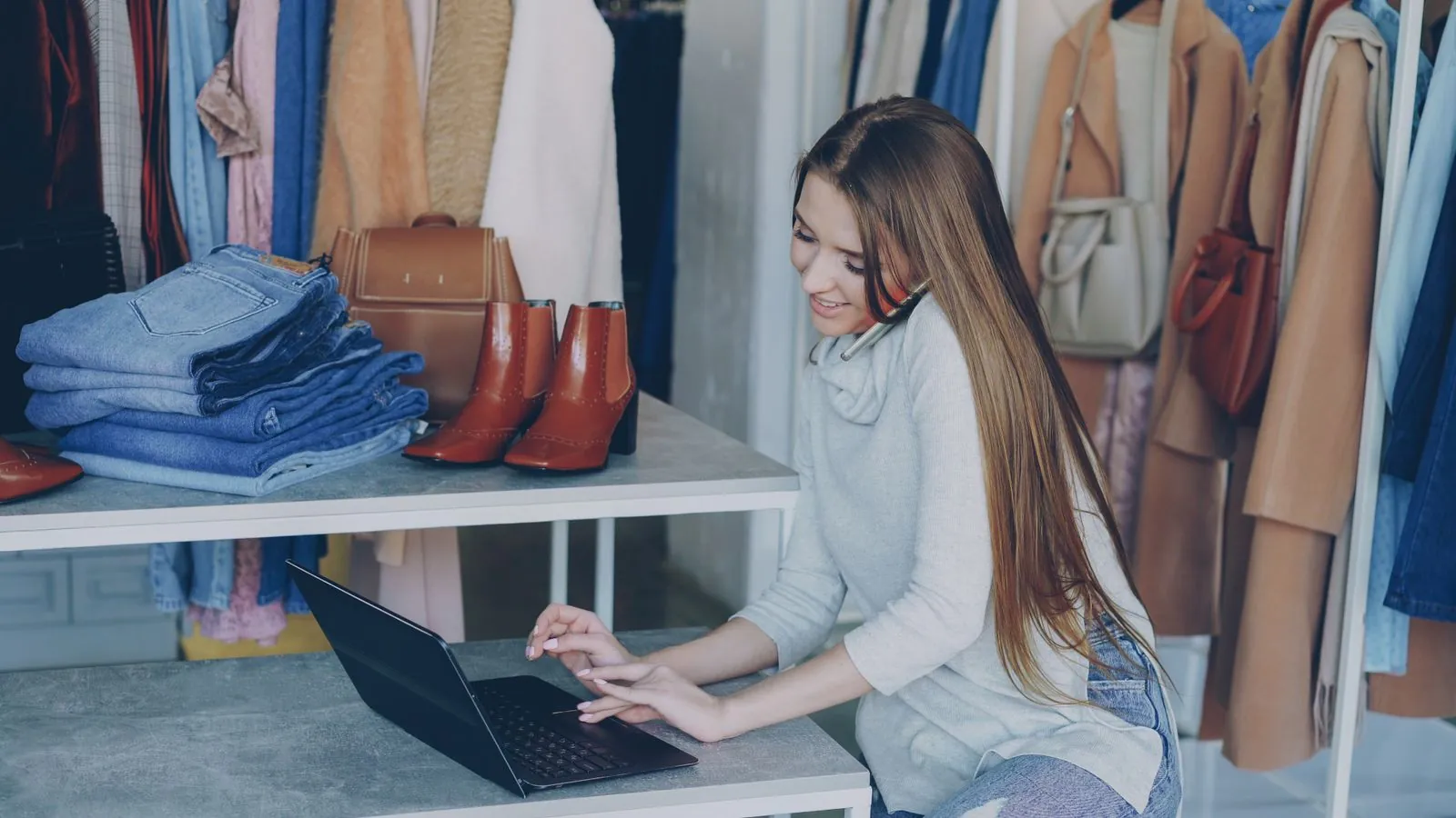 Une commerçante au téléphone devant son ordinateur, dans sa boutique