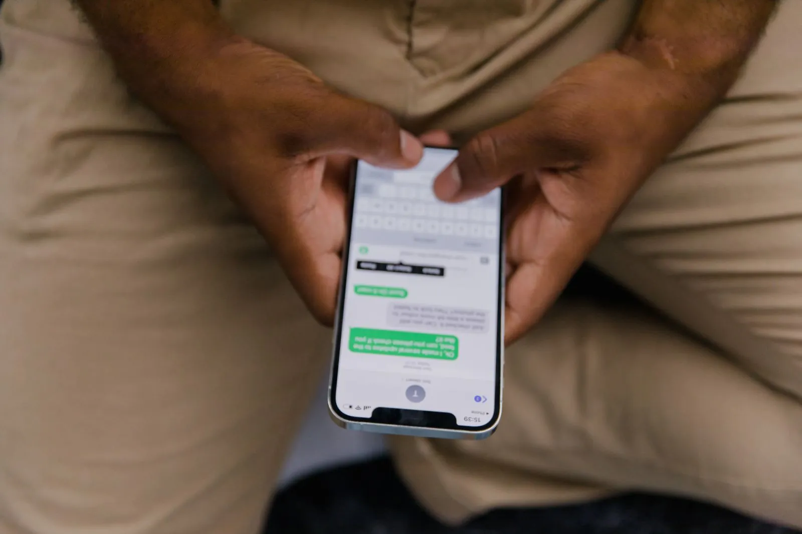 Des mains tiennent un téléphone affichant une conversation de messagerie
