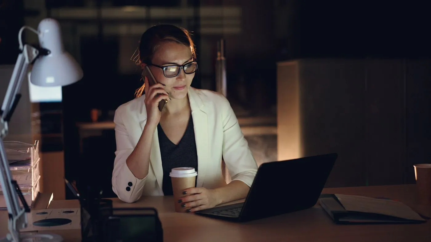 Une responsable répond à un message tard le soir, depuis son bureau